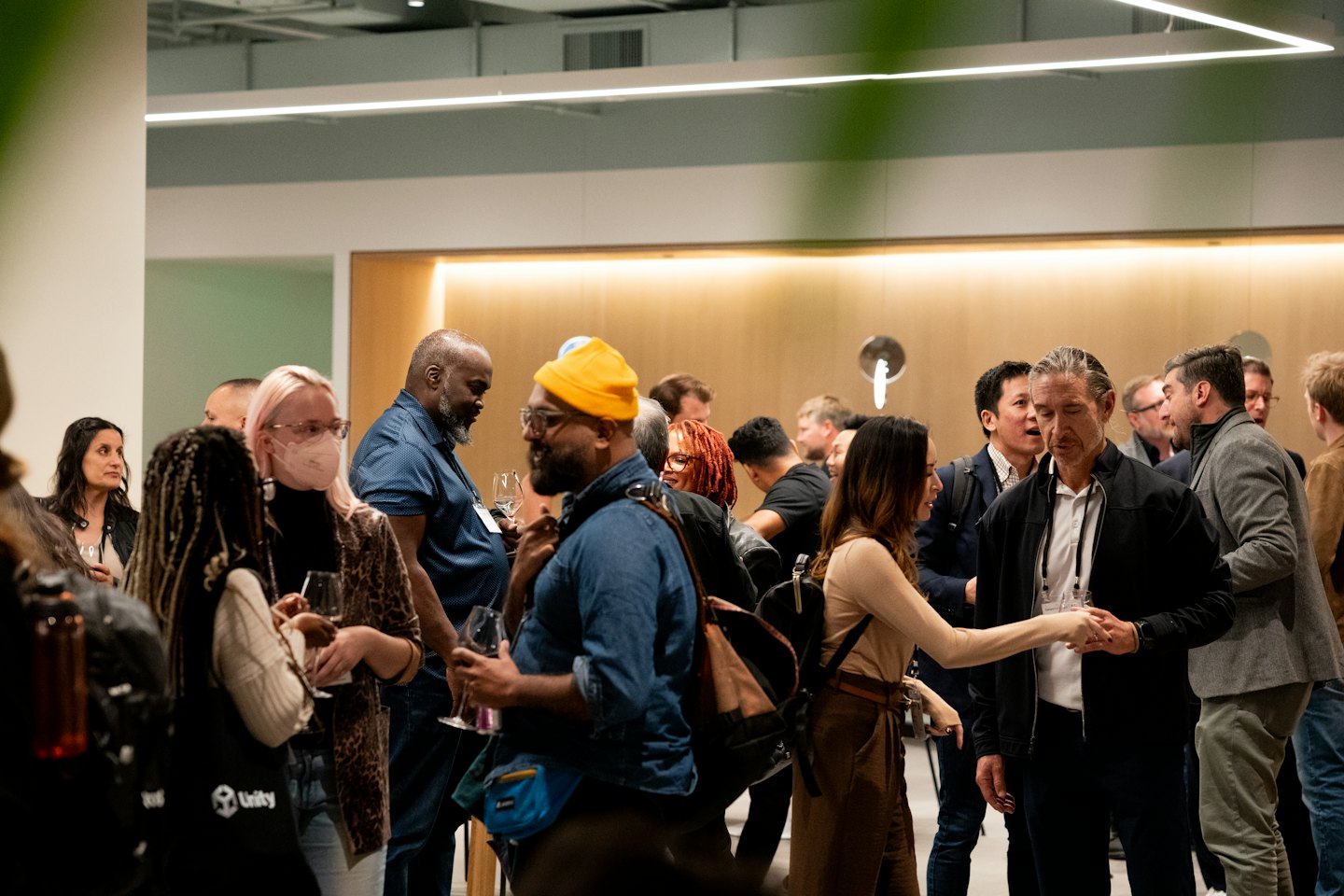 Professionals networking and holding wine glasses at an indoor event.
